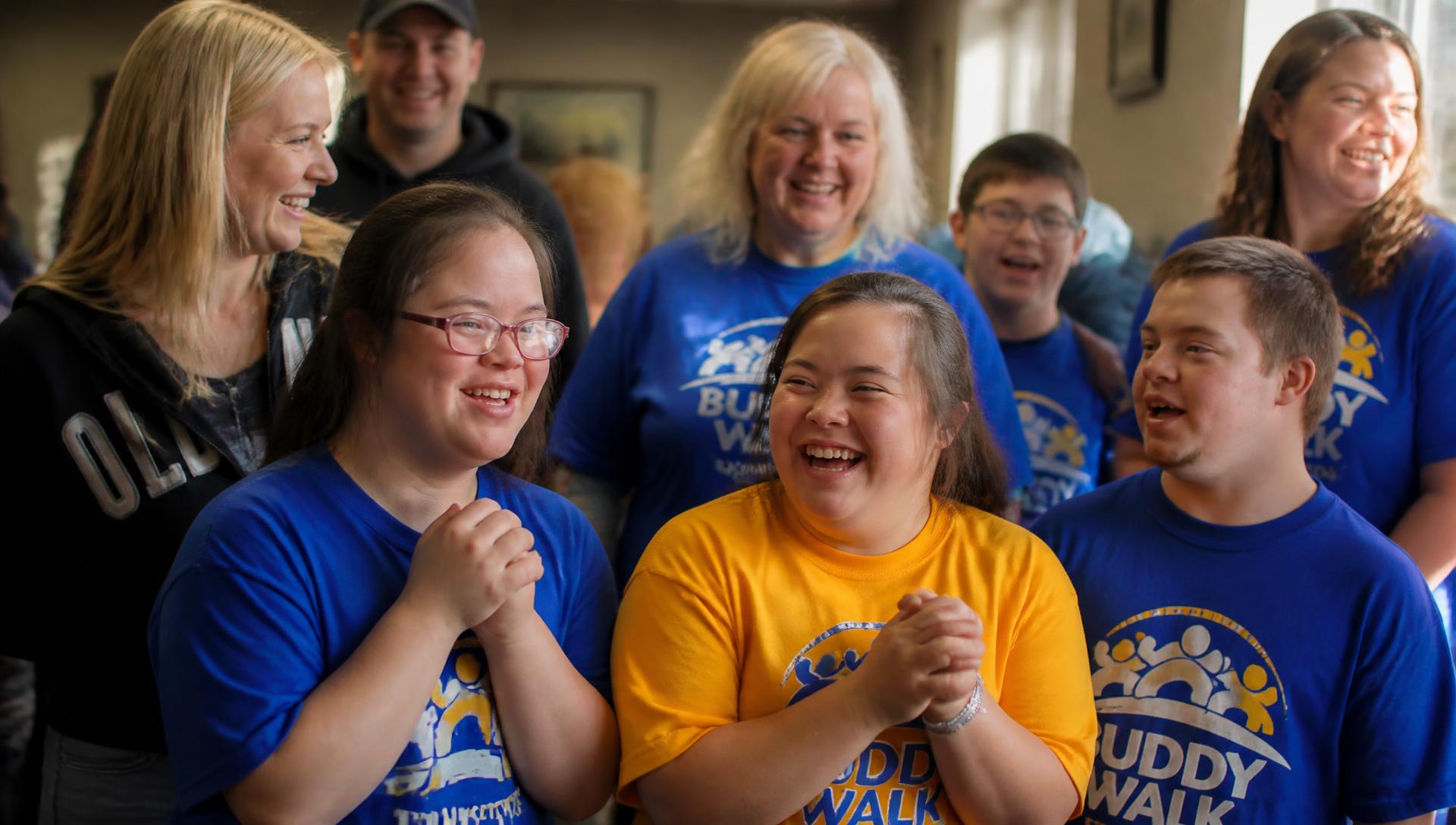 Members of the Buddy House community laughing together in blue and yellow DSSKY shirts